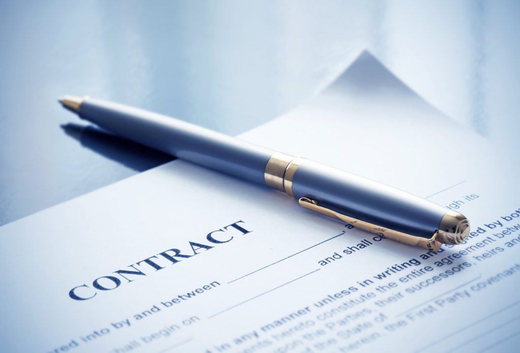 a contract lying on a table with a pen written by a contract lawyer