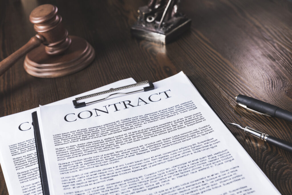 contract law conceptual image - juridical contract on wooden table with pen and hammer